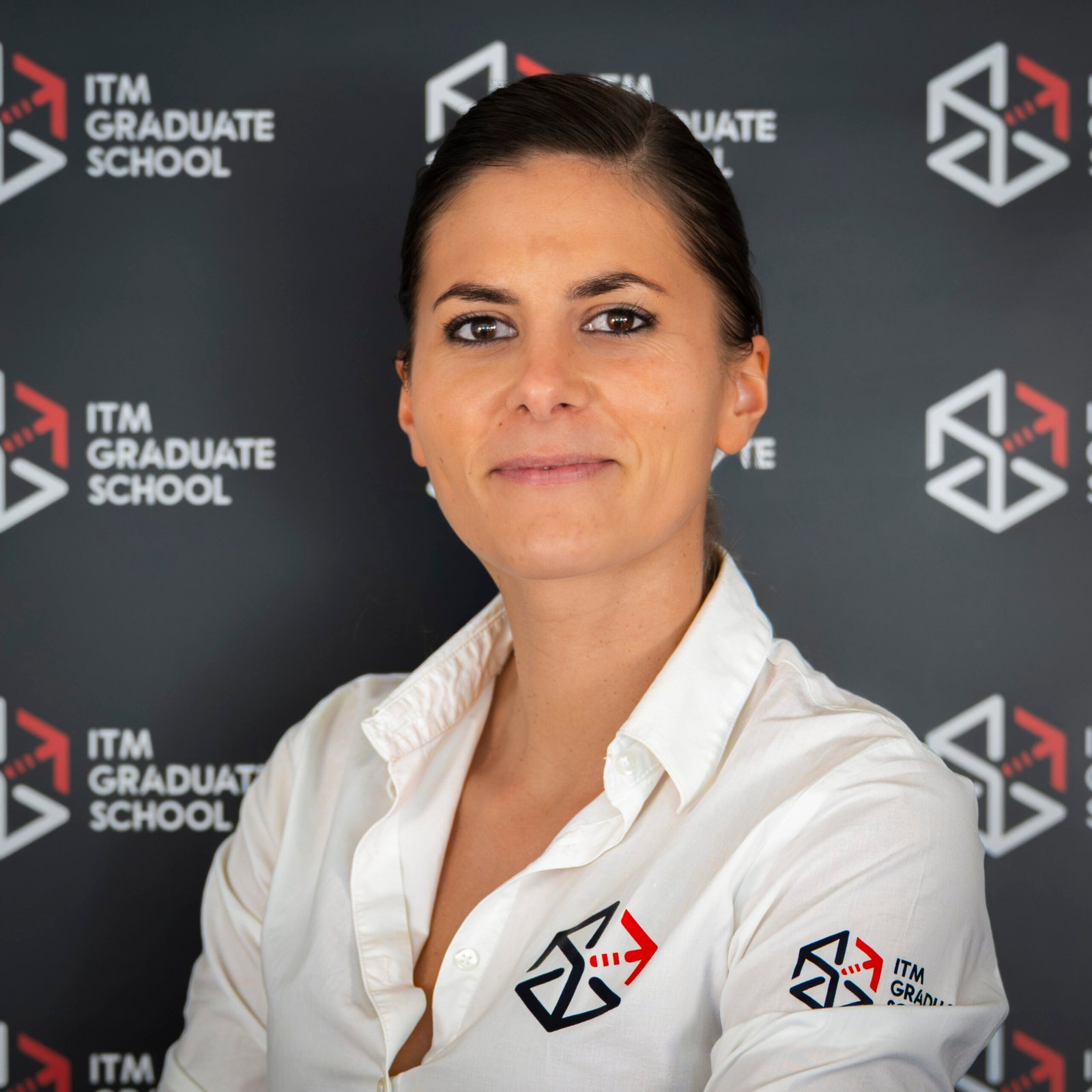 La directrice de l’ITM Graduate School devant le mur de logos de l’école
