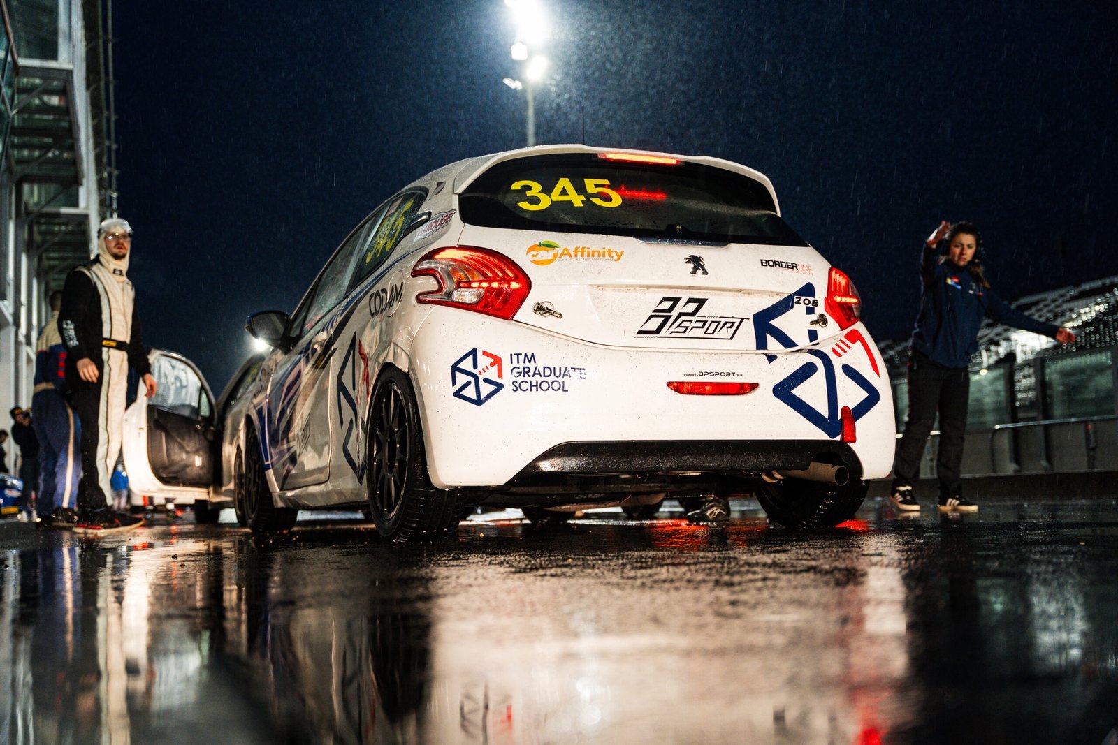 Voiture de course aux couleurs de l’ITM Graduate School, de nuit sous les projecteurs