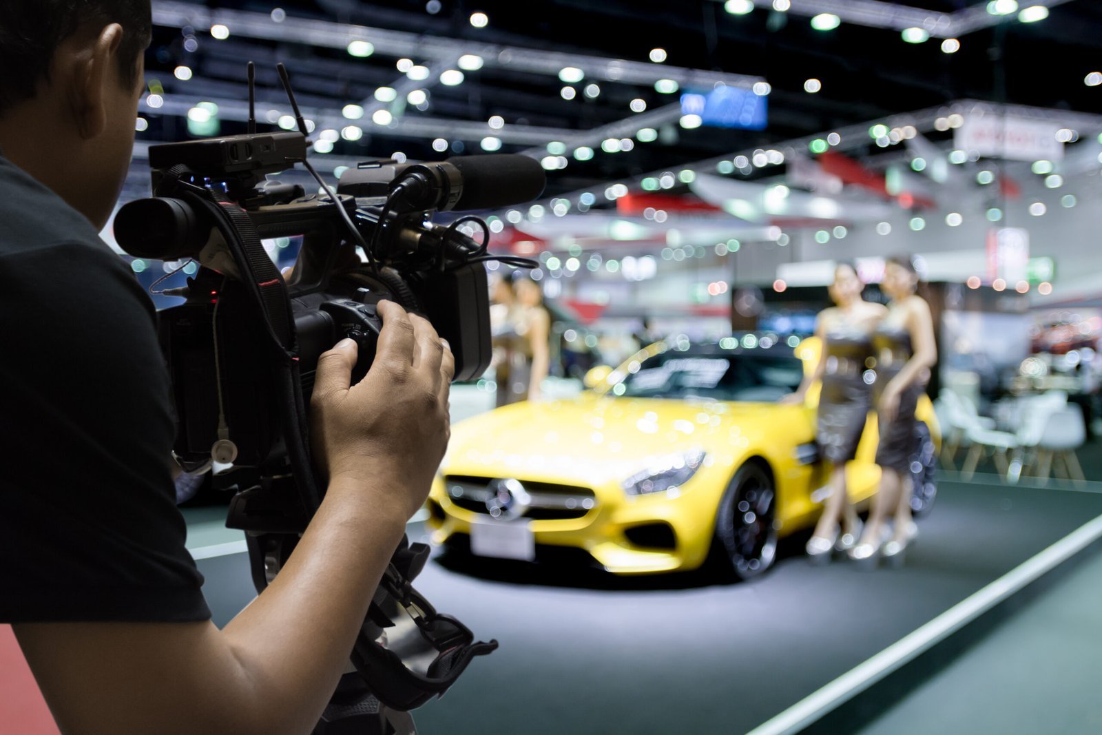 Caméraman filmant une voiture de sport sur un salon automobile